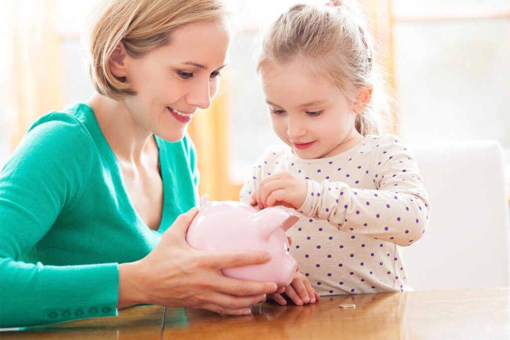 Mother and daughter putting money into piggy bank
