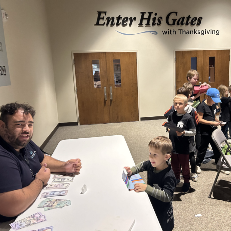 Line of children waiting to exchange money with David using their homemade wallets.