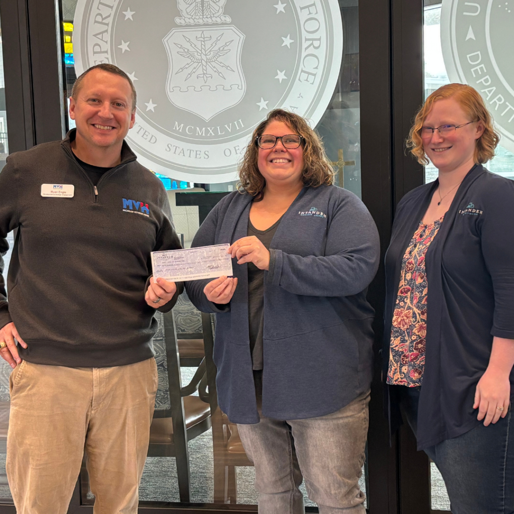 Check presentation with Kourtney and Mackenzie handing a check to Ryan from the Michigan Veterans Home in Grand Rapids.