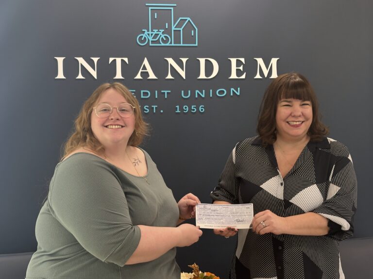 Lexi from Intandem Credit Union presents a donation check to Kyle at the Children’s Advocacy Center of Kent County, showing how to support local nonprofits.