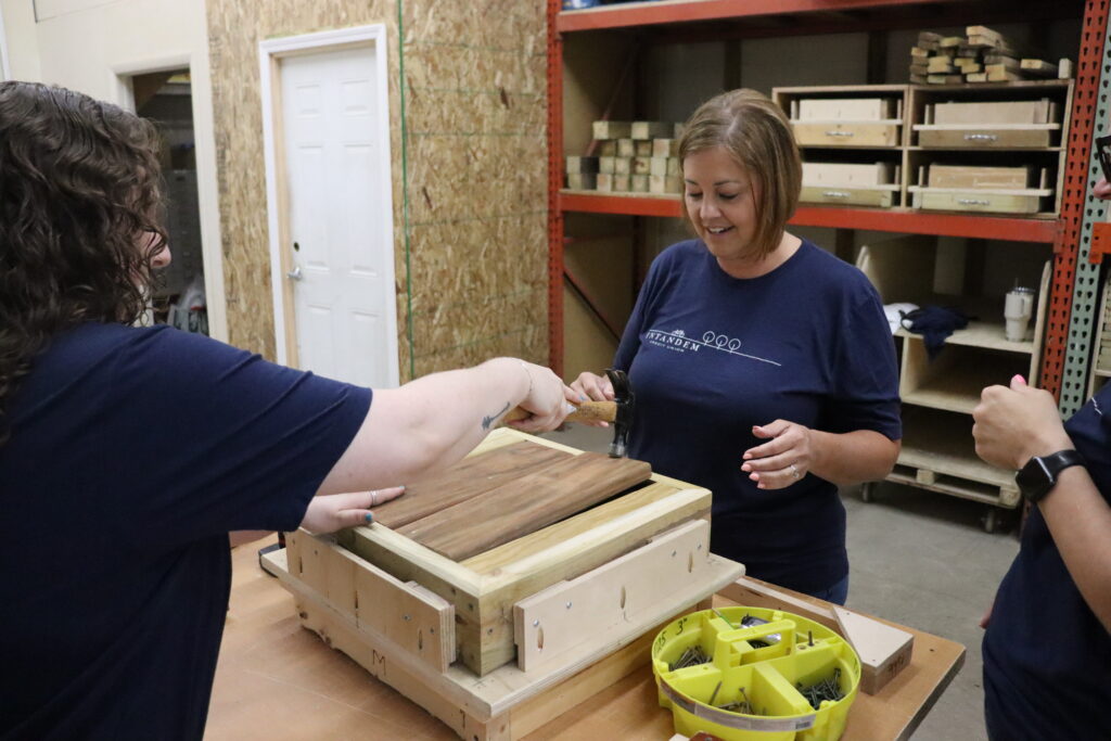 Intandem Credit Union volunteers working together to build handcrafted tables during a community involvement project with Home Repair Services.