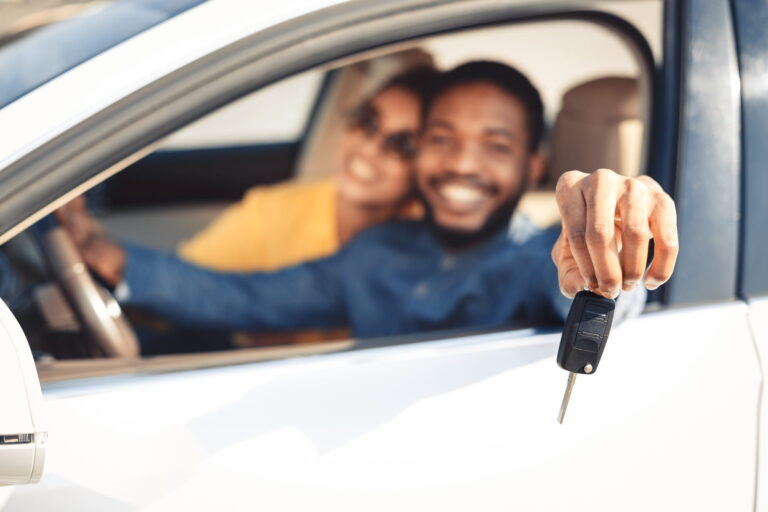 A young adult shows off the keys to their new car.